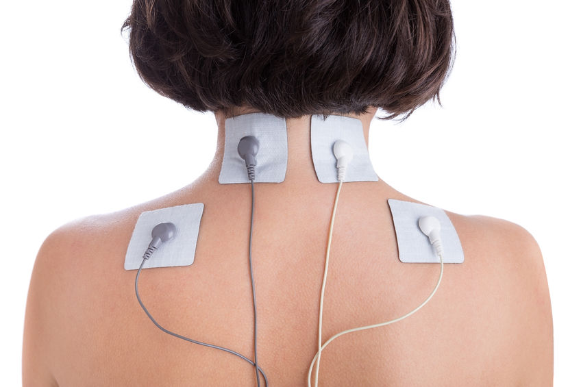 Woman with electrode pads on neck and back receiving electrical muscle stimulation therapy